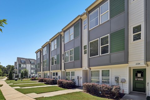 A row of modern townhouses with green and grey siding and white trim.