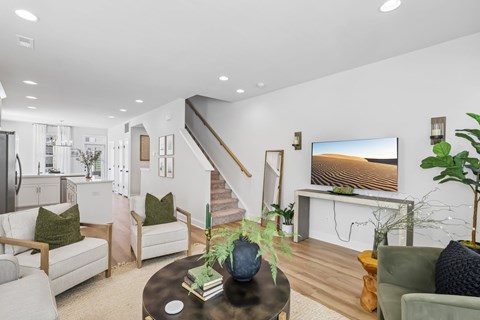 A living room with a staircase and a flat screen TV.