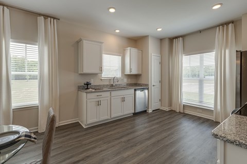 A kitchen with white cabinets and a wooden floor.