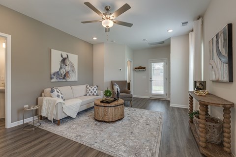 A living room with a white couch and a painting of a horse on the wall.