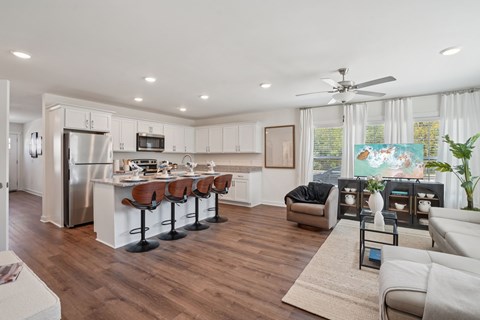 A modern kitchen with white cabinets and a wooden floor.