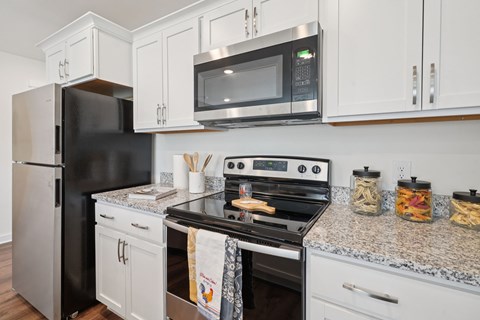A black refrigerator sits next to a black microwave in a kitchen.
