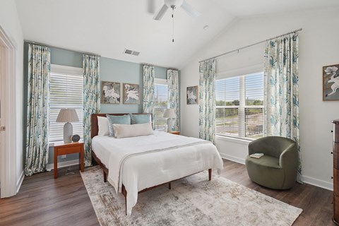 A bedroom with a large bed and a chair.