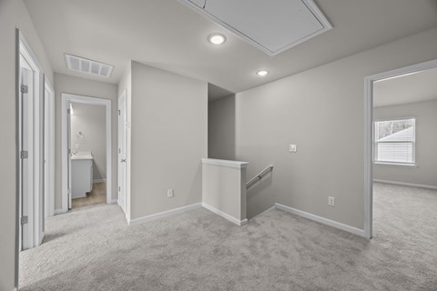 A spacious room with a carpeted floor and a window with blinds.