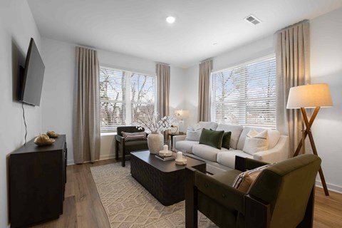 A living room with a dark brown sofa, a wooden coffee table, and a television on the wall.