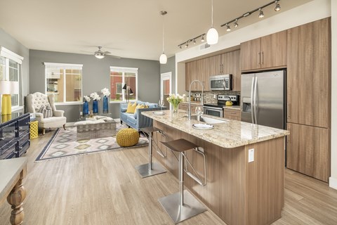 an open kitchen and living room with a marble counter top