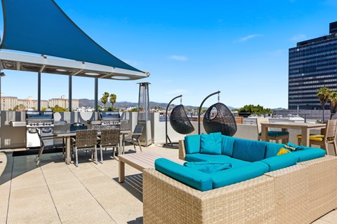 A blue canopy provides shade for a patio with a blue couch and chairs.