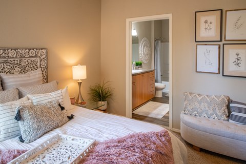 a bedroom with a bed and a chair and a bathroom