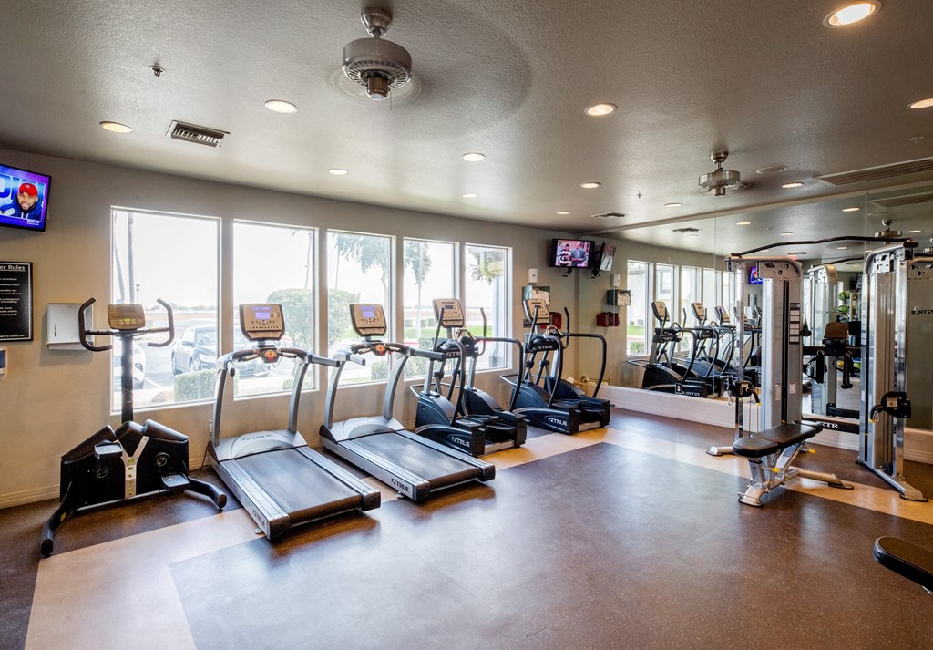 a gym with cardio equipment and windows in a building