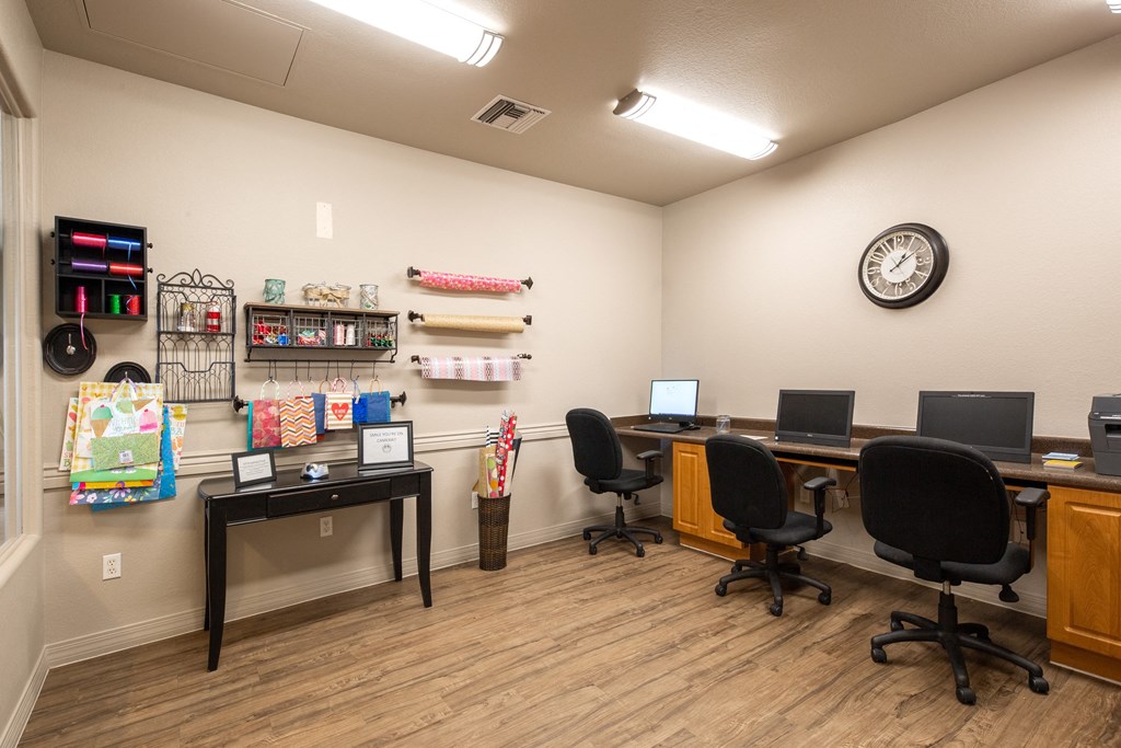 a study room with three computers and chairs and a clock on the wall