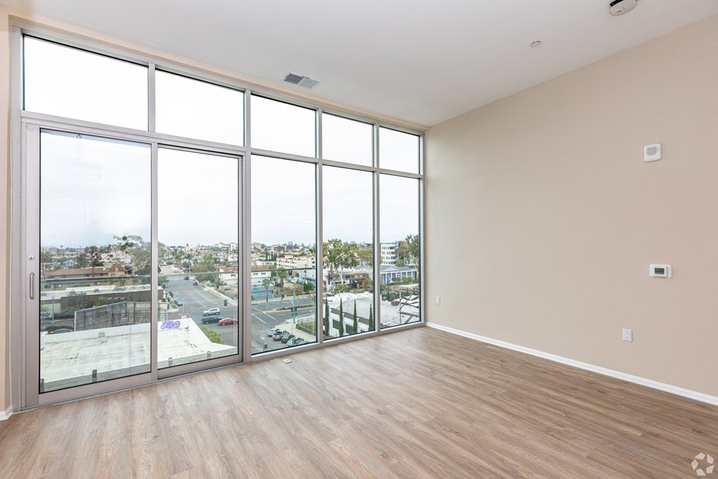 an empty living room with floor to ceiling windows and a city view