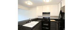 a kitchen with white cabinets and black countertops