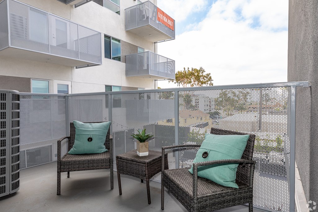two wicker chairs sitting on a balcony with green pillows