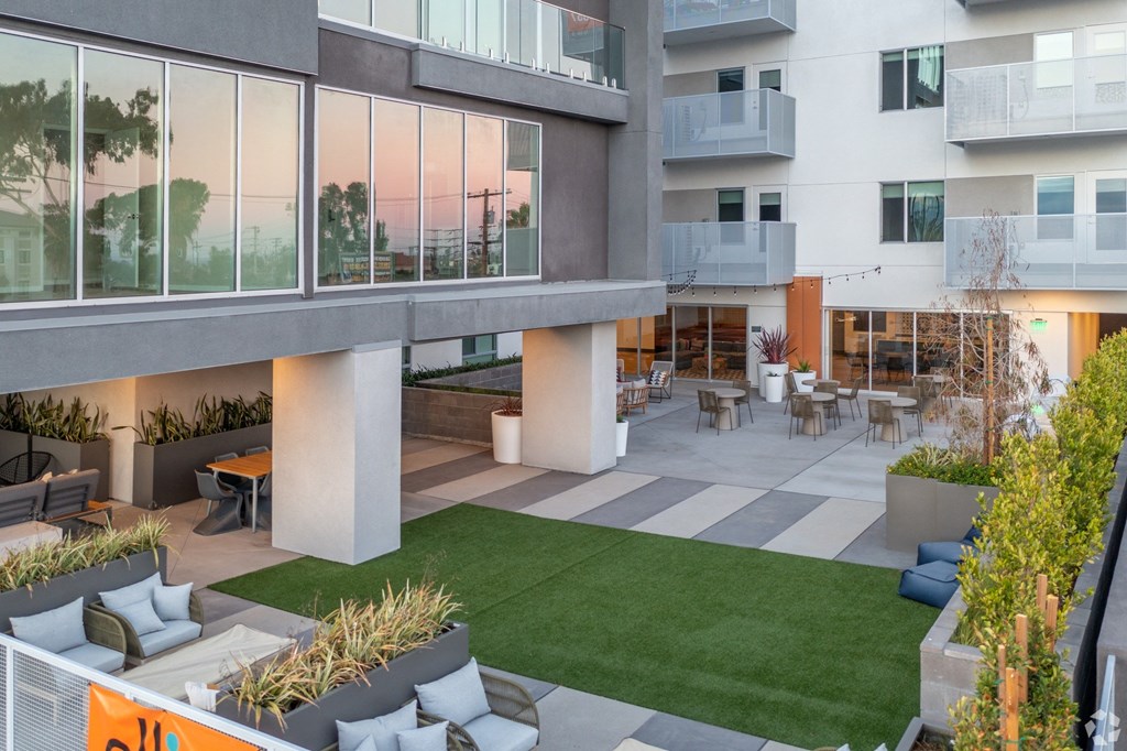 an open courtyard of an apartment building with grass and chairs