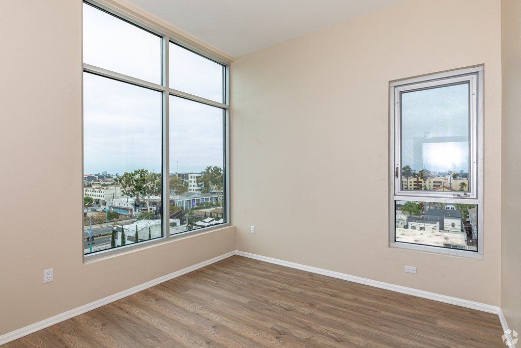 an empty living room with large windows and a city view
