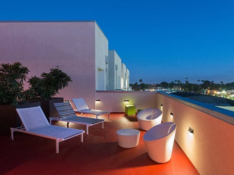 a rooftop terrace with lounge chairs and a pool at night
