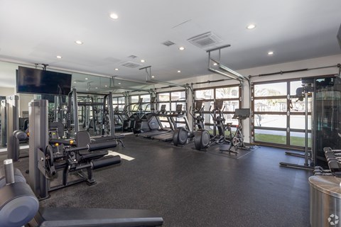 A gym with a variety of equipment including treadmills, weights, and exercise machines.