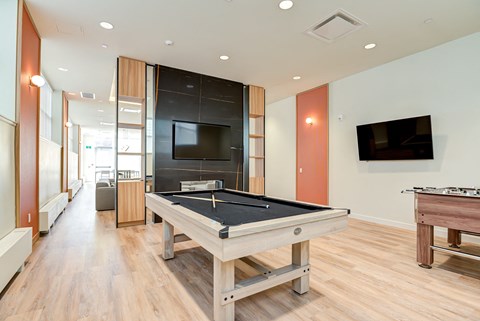 A pool table in a room with a TV mounted on the wall.