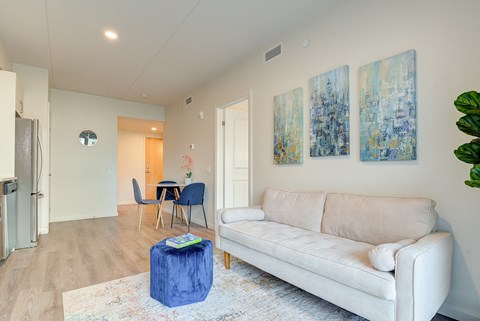 A living room with a white couch and a blue ottoman.