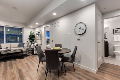 A modern dining room with a table set for two and a clock on the wall.