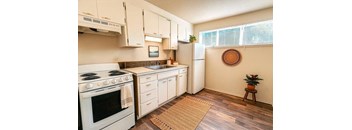 A kitchen with white appliances and wooden floors.