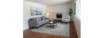 A living room with a grey couch, a coffee table, and a painting on the wall.
