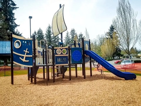 A playground with a slide and a wooden structure with a blue and white anchor design.