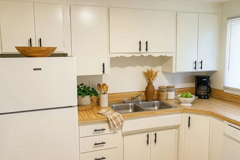 A kitchen with white cabinets and a wooden countertop.