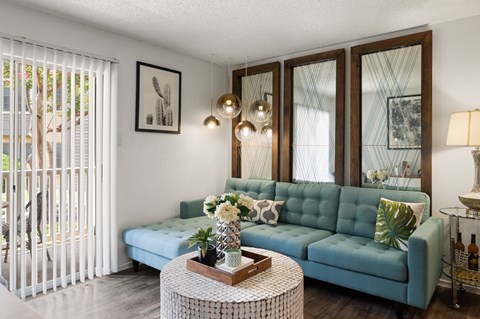 A living room with a blue couch, a coffee table, and a painting on the wall.