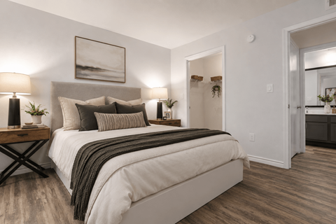 A well-lit bedroom with a large bed and a painting on the wall.