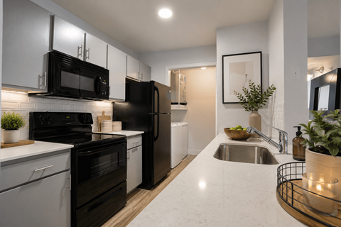 A modern kitchen with black appliances and white cabinets.