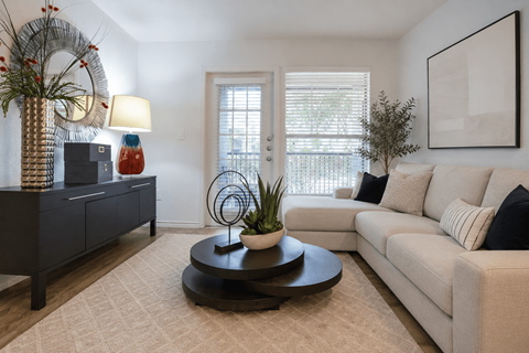 A living room with a white couch, a coffee table, and a side table with a lamp and a vase.