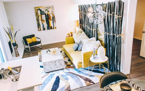 A living room with a yellow couch and a white coffee table.