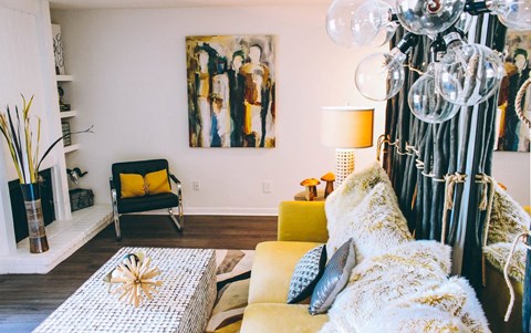 A living room with a yellow couch and a painting on the wall.