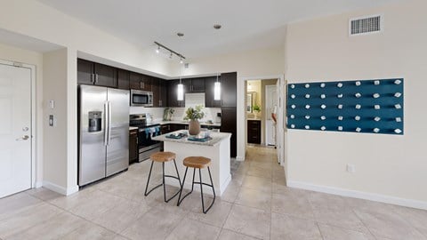 A kitchen with a refrigerator, stove, and bar stools.