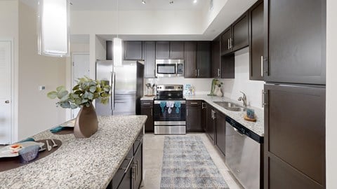 A modern kitchen with dark brown cabinets and a granite countertop.