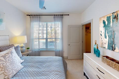 A bedroom with a bed, nightstand, and a painting on the wall.