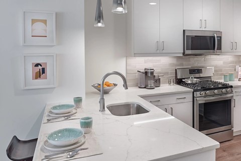 A modern kitchen with a marble countertop and stainless steel appliances.