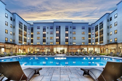 A large swimming pool in front of a multi-story residential building.