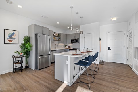 A kitchen with a white island and blue chairs.