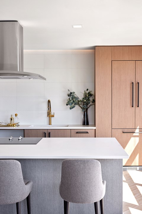 A modern kitchen with a white countertop and grey bar stools.