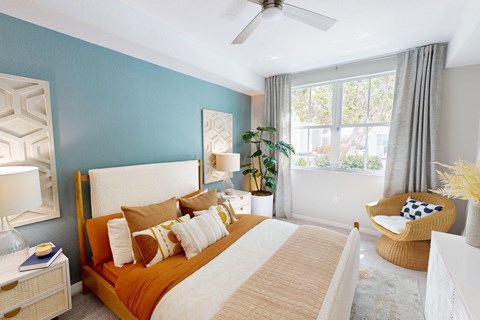 A bedroom with a bed, chair, and a ceiling fan.