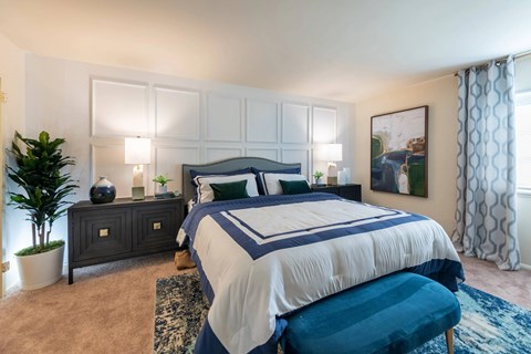 A bedroom with a large bed and a painting on the wall.
