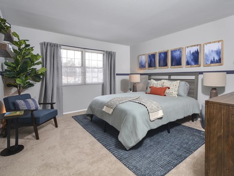 A bedroom with a bed, chair, and pictures on the wall.