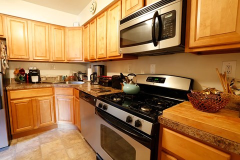 A kitchen with a stove, oven, microwave, and cabinets.