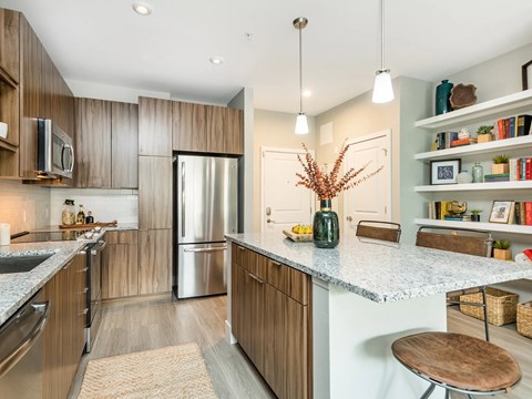 A kitchen with a refrigerator, microwave, and wooden cabinets.