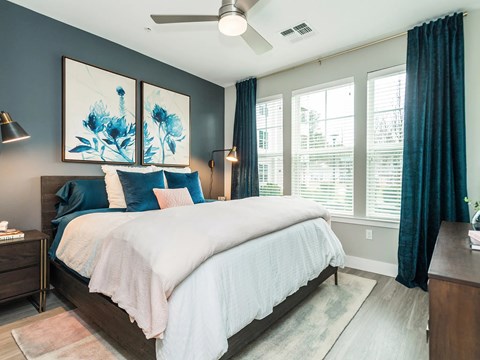 A bedroom with a large bed and a ceiling fan.