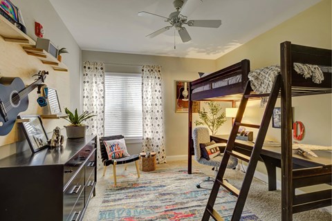 A room with a bunk bed and a chair with a colorful rug.