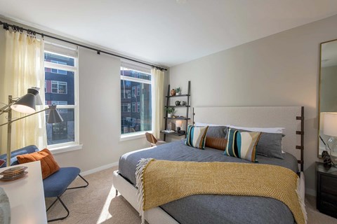 A bedroom with a bed, a chair, and a window with curtains.