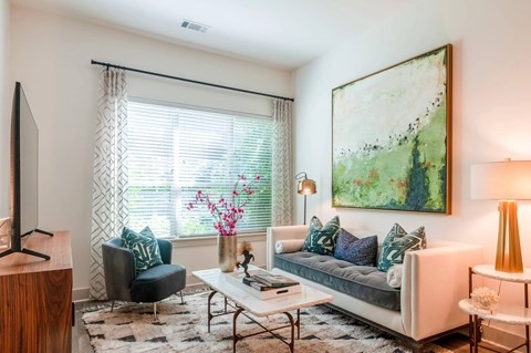 A living room with a couch, chair, and a painting on the wall.
